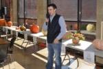 Male student with microphone talking in front of tables with pumpkins